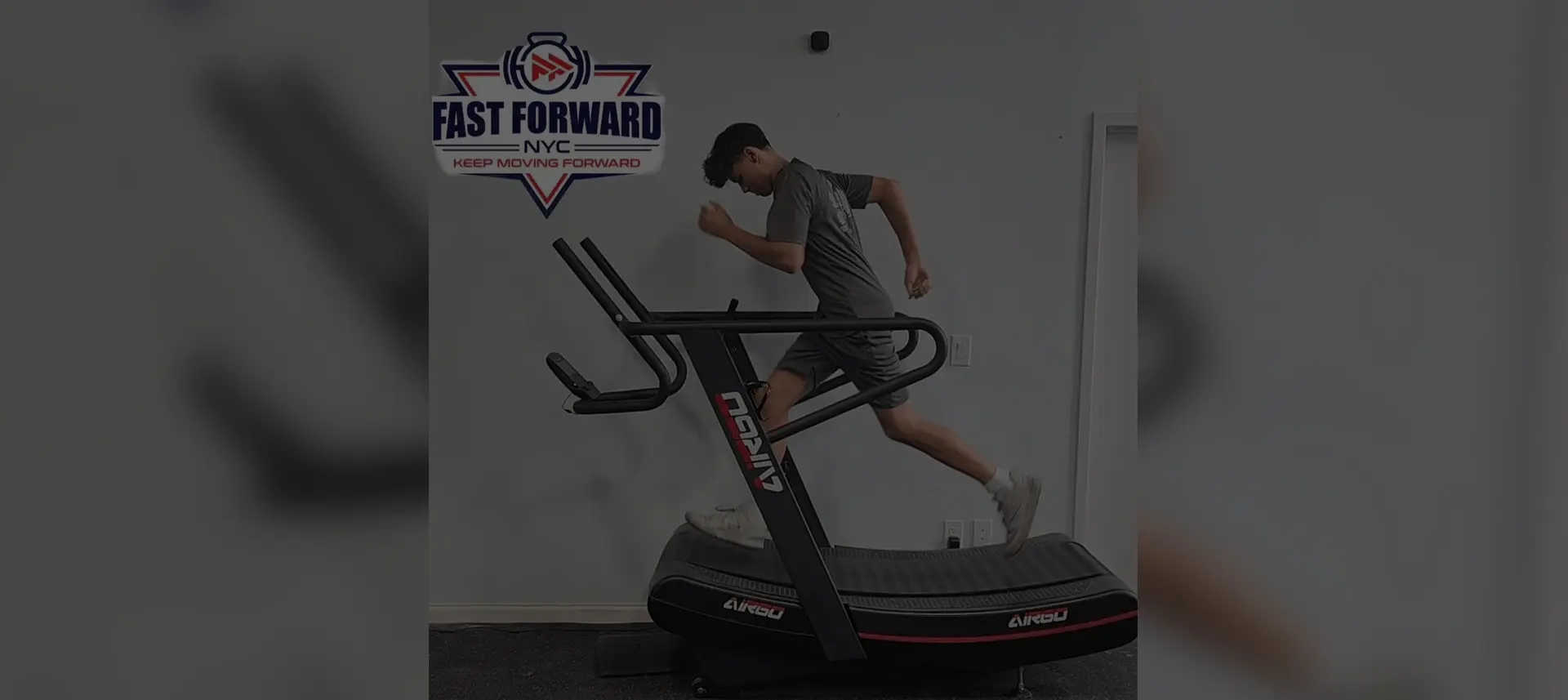 Man running intensely on a curved treadmill indoors.