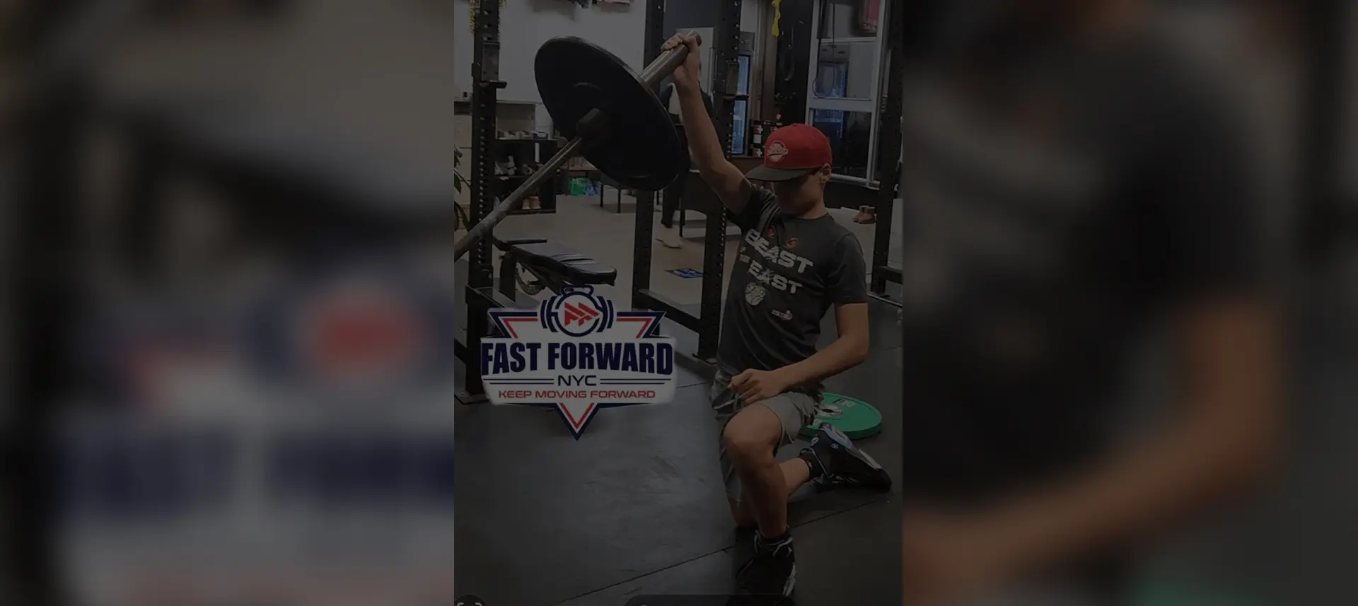 Man working out with dumbbells in a gym under a motivational sign.