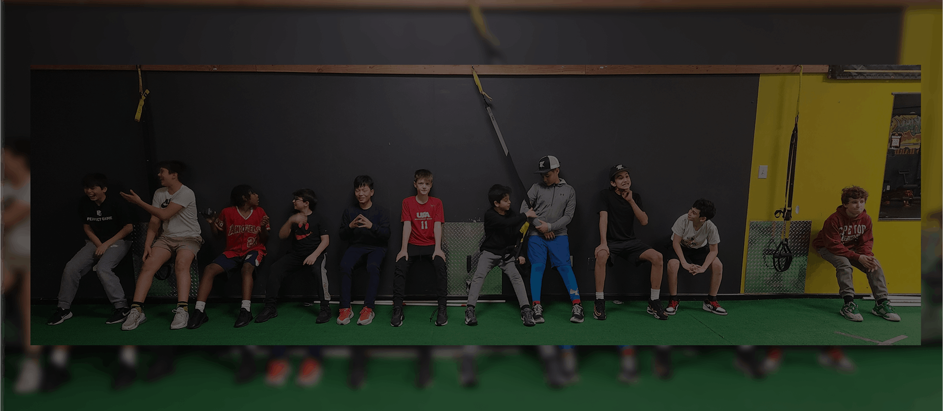 Group of people sitting on a bench indoors, some wearing masks.