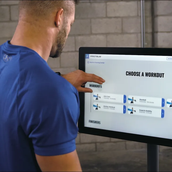 Man interacting with a touchscreen to choose a workout.