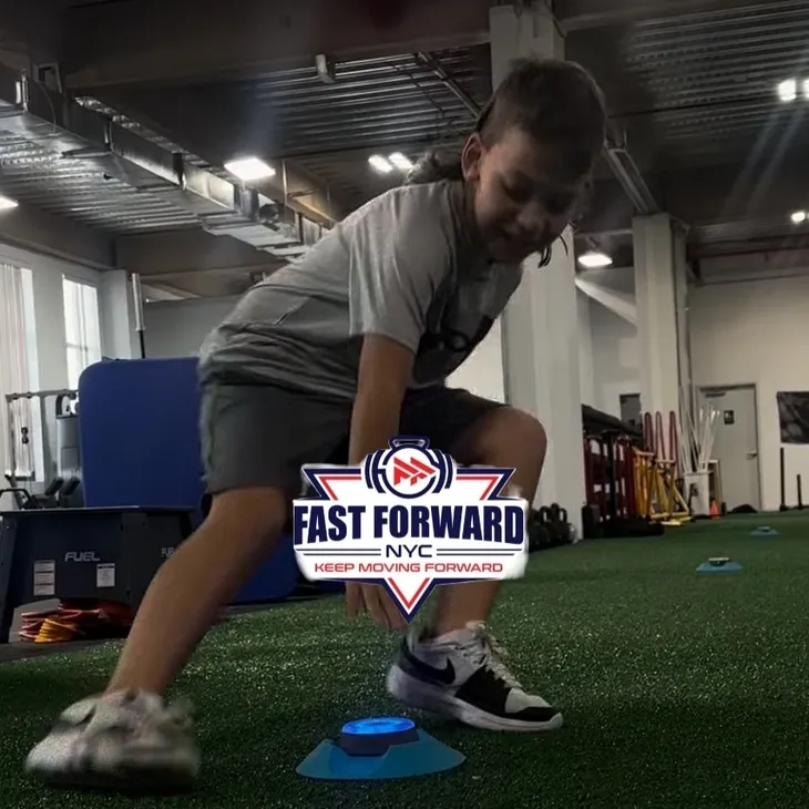 A young boy practicing agility drills indoors with cones.