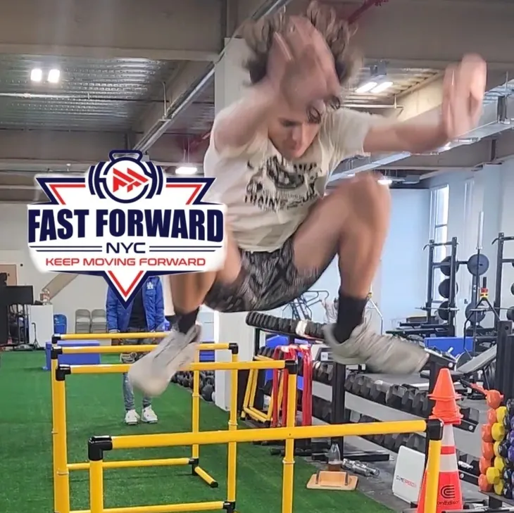Athlete jumping over hurdles indoors during a fast-forward training event.