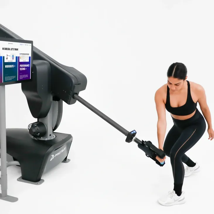 Woman using VR controller with robotic arm for immersive experience.