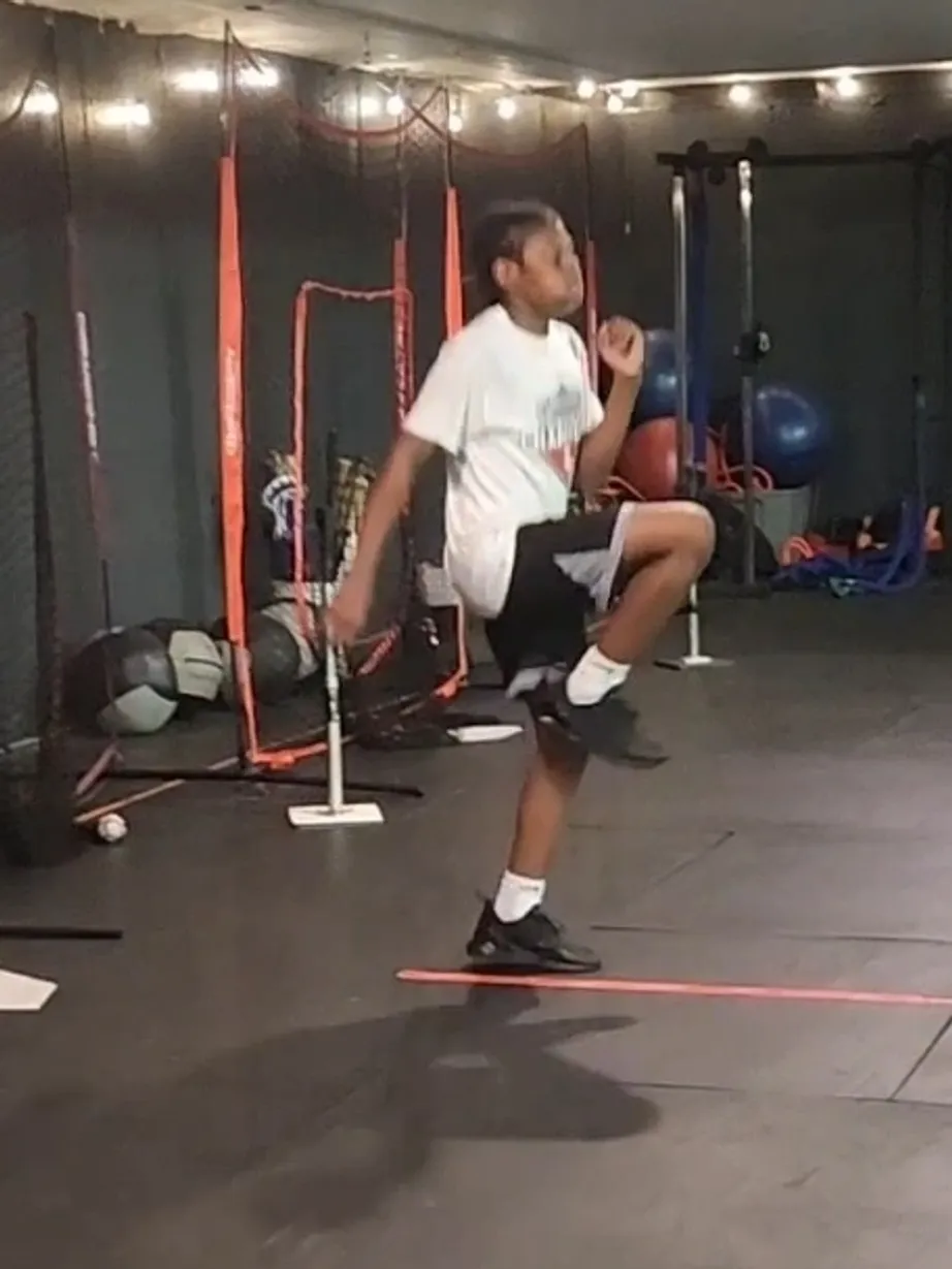 Athlete performing high-knee drills indoors with resistance bands.
